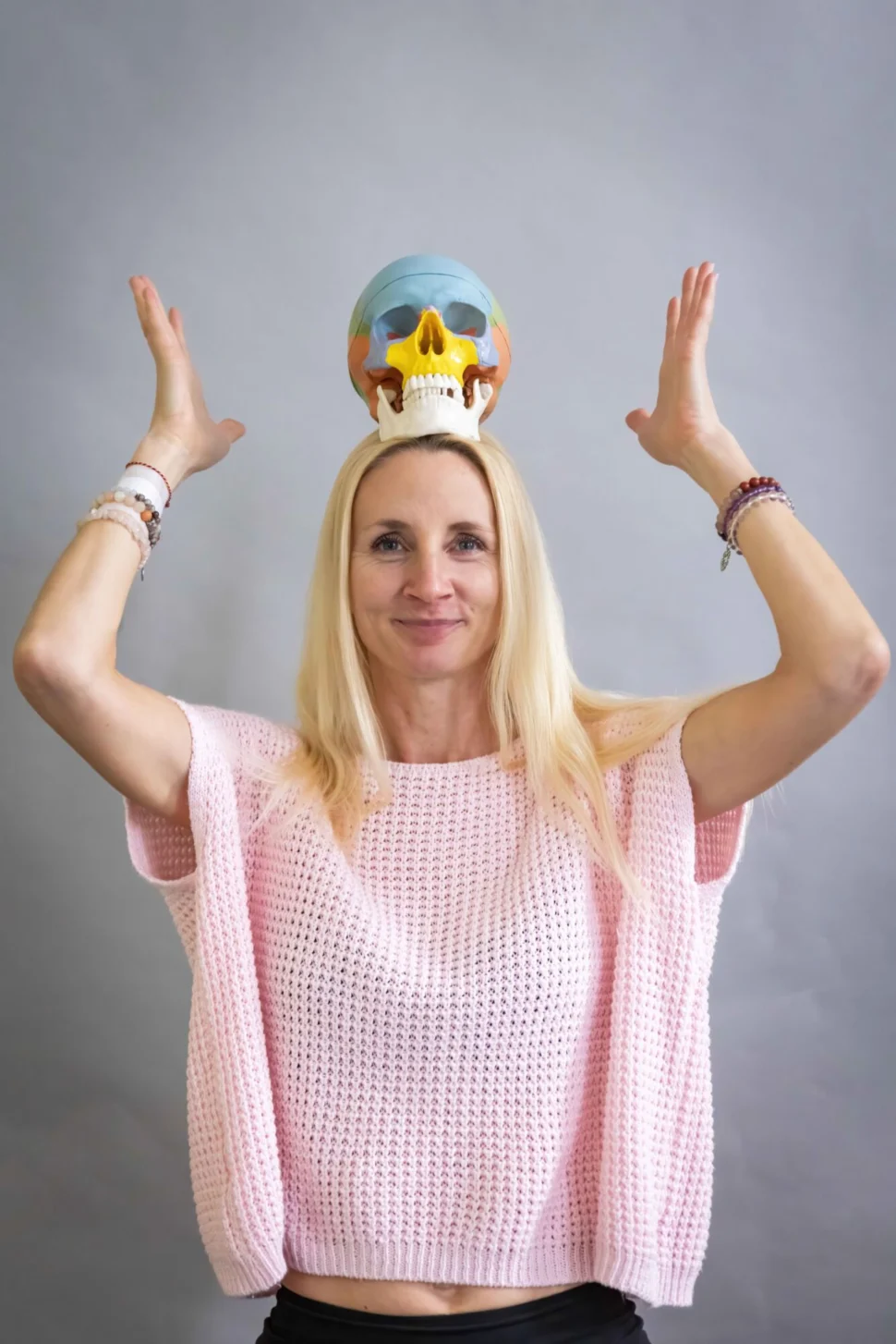 Certifikovaná lektorka Martina Bajerová z online programu Facelift Yoga Experience s barevným anatomickým modelem lebky na hlavě, který slouží jako pomůcka pro pochopení struktury obličeje.
